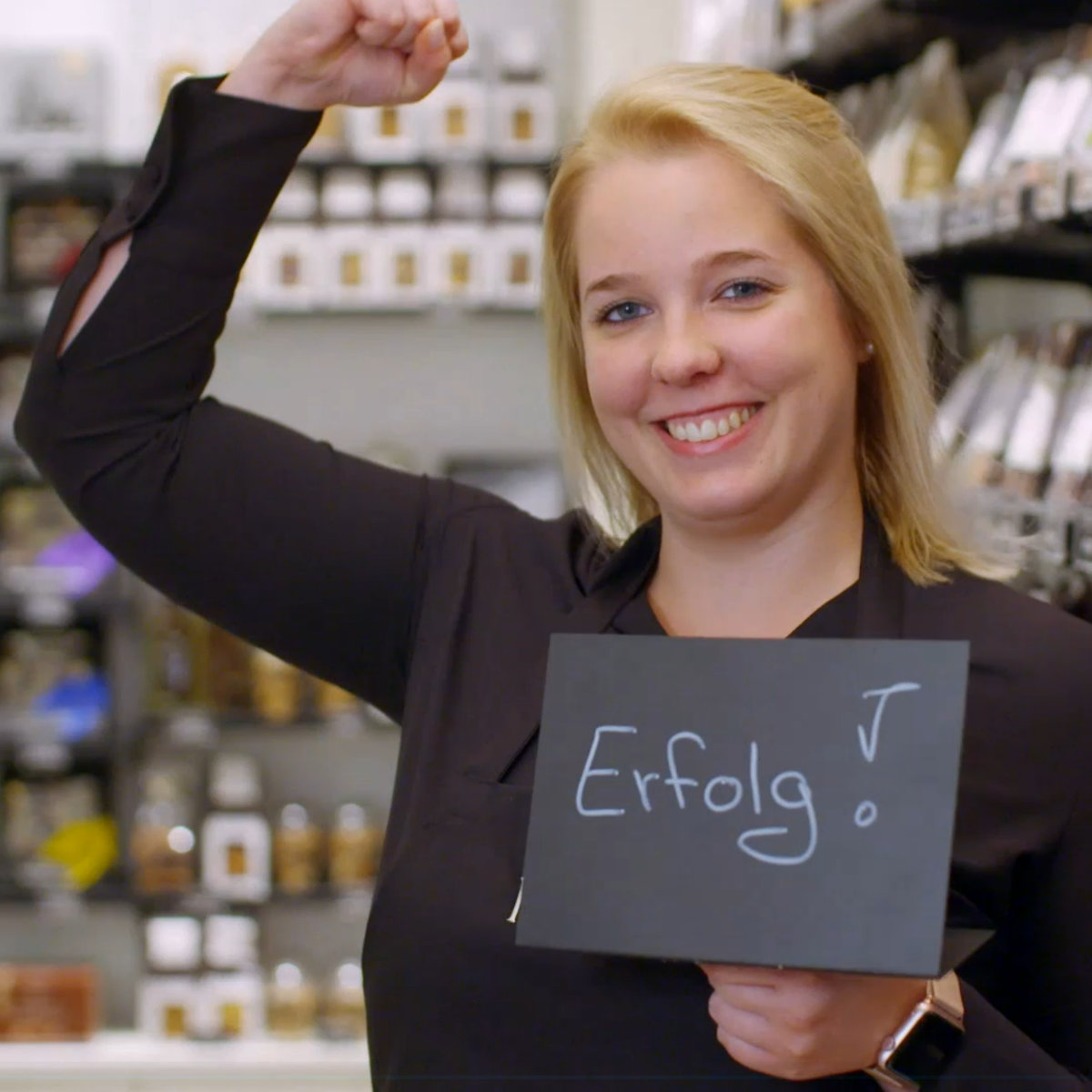 AV22 film – Eine Frau hält ein Schild mit dem Wort „Erfolg“ vor sich