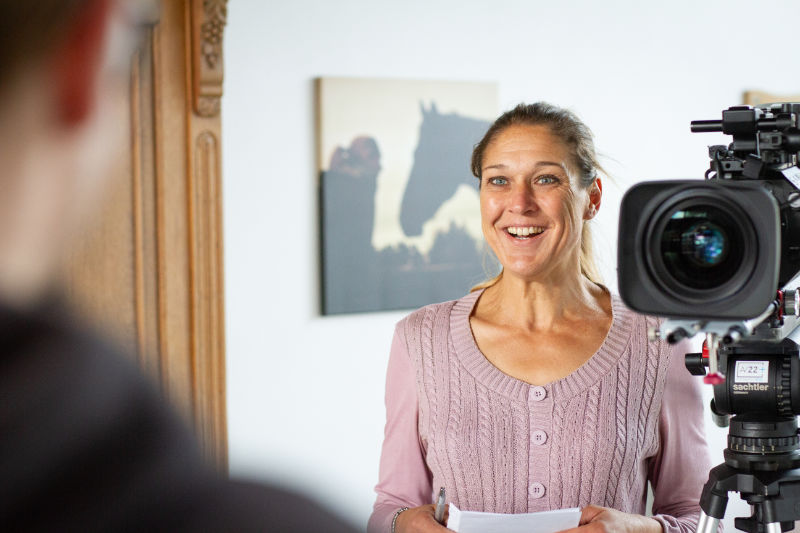 AV22 learn – Anja Meyer steht neben einer Kamera und interviewt eine Person