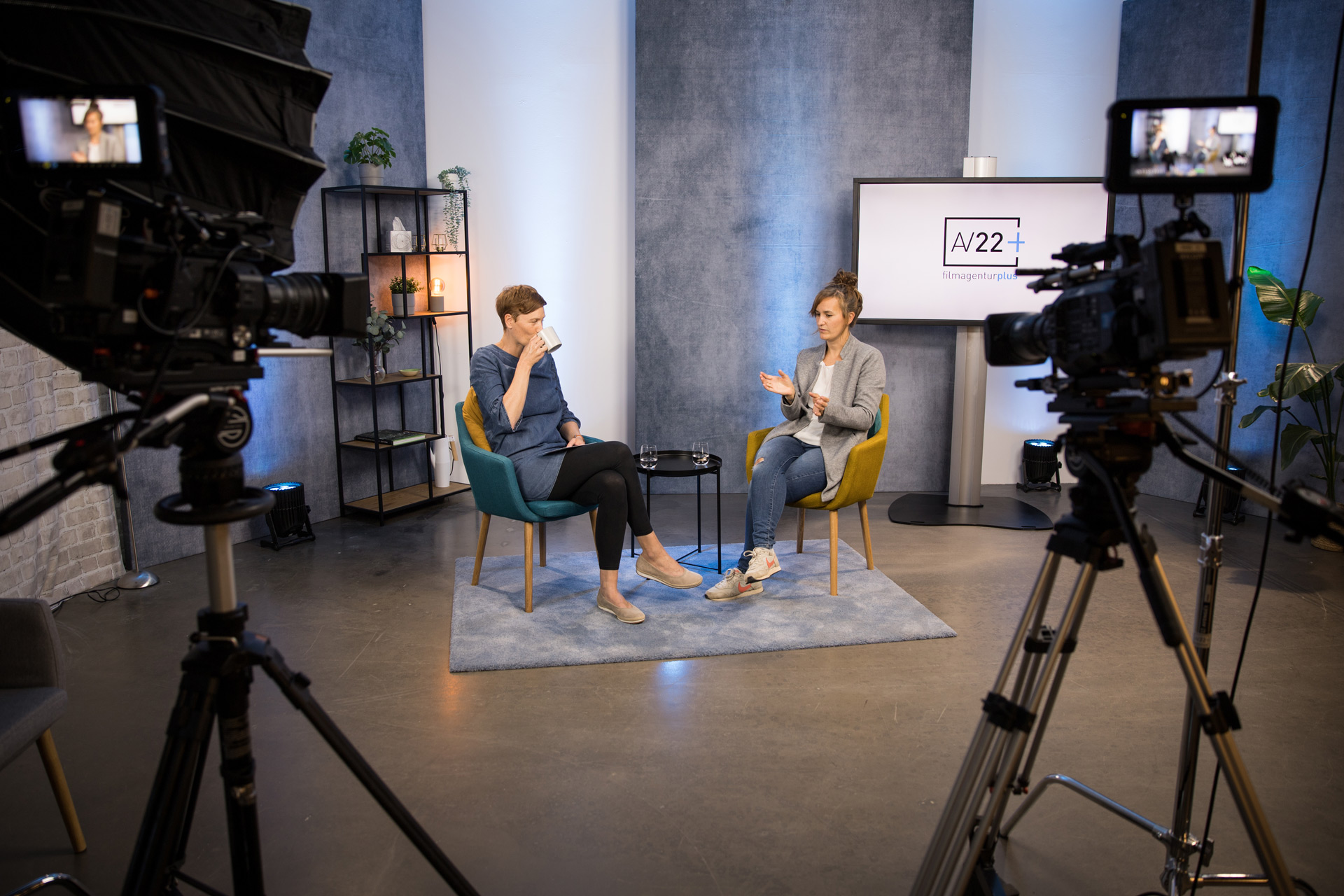 AV22 studio – Johanna und Franka sitzen in einem Videostudio in moderner Studioumgebung